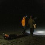 Dwóch mężczyzn nocą na zamarzniętym jeziorze w światłach czołówek