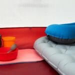 Minimalistyczne wyposażenie w namiocie: śpiwór, mata, poduszka i garnek