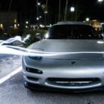 Srebrne sportowe auto nocą otoczone dynamicznymi smugami świateł