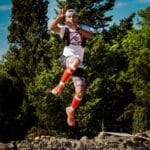 Biegacz skacze w dół na leśnym szlaku podczas zbiegu terenowego