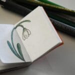 Szkic przebiśniegu w małym szkicowniku z przyborami do rysowania w tle