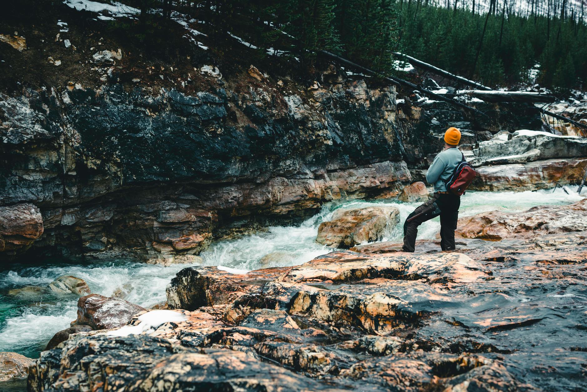 Trekker stoi nad rwącą rzeką w górskim lesie