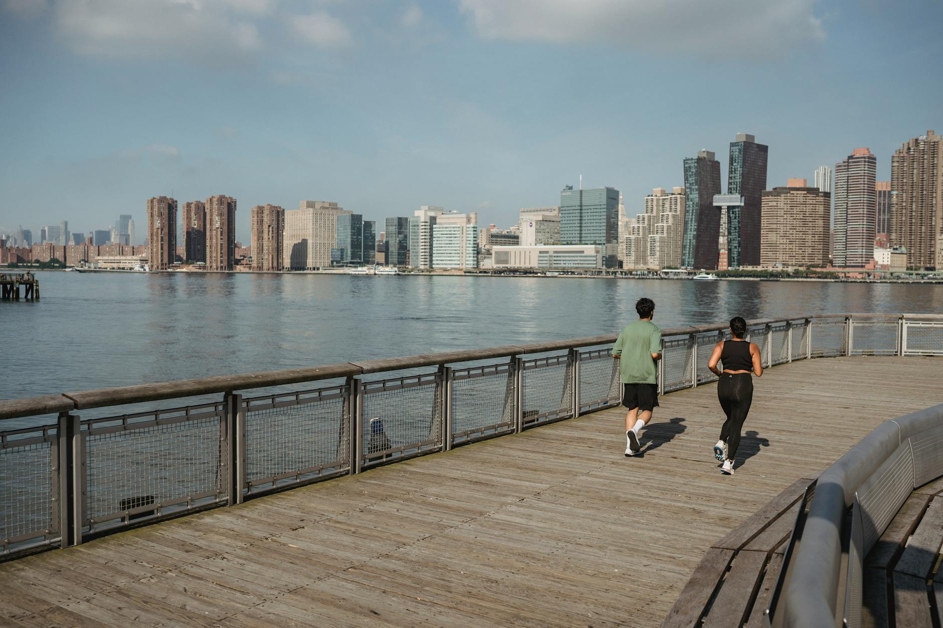 Biegacze nad rzeką na tle miejskiej panoramy jesienią