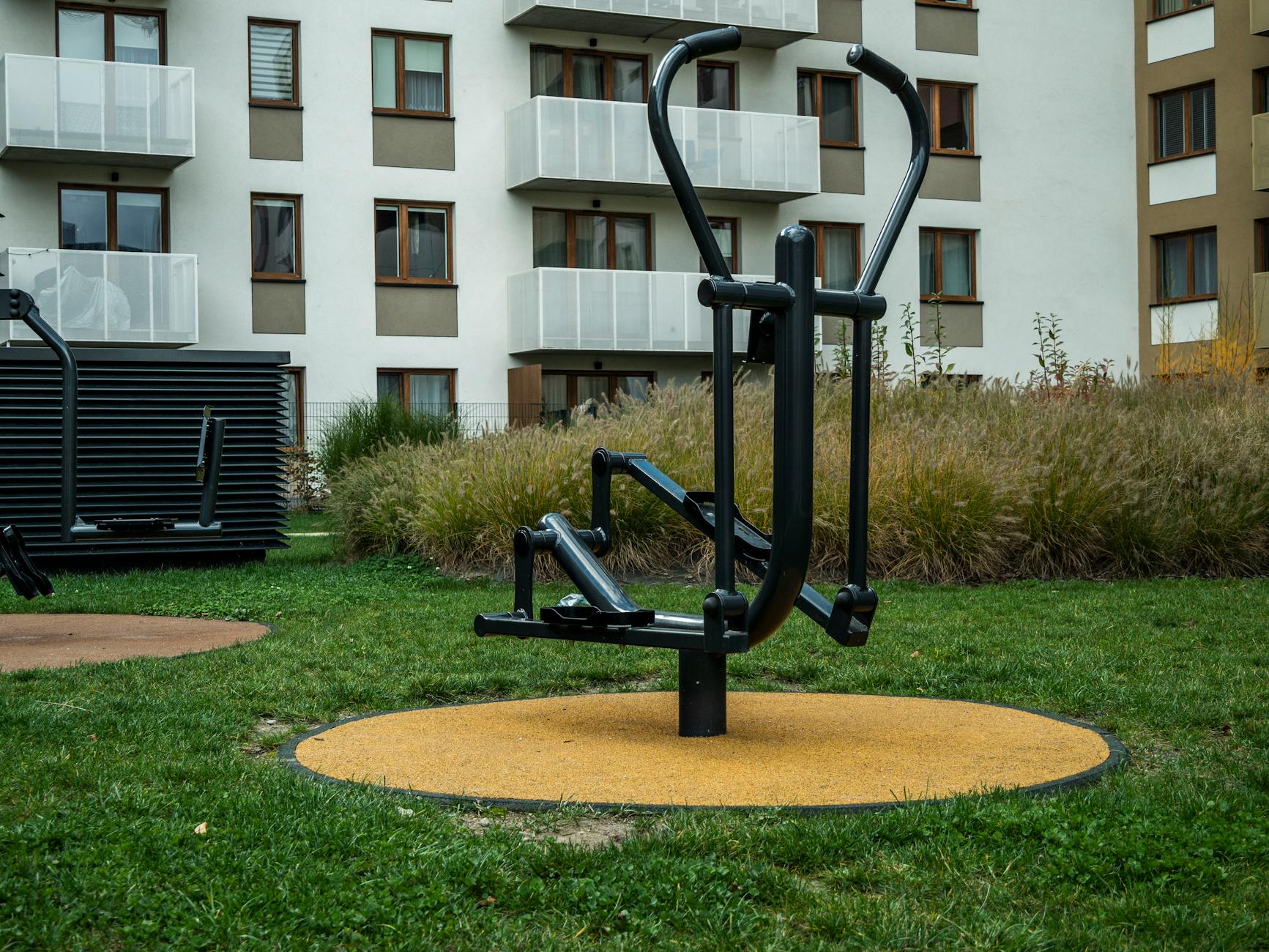 Plenerowa siłownia między nowoczesnymi blokami w jesiennym mieście