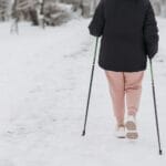Osoba z kijkami idzie po zaśnieżonej ścieżce zimą