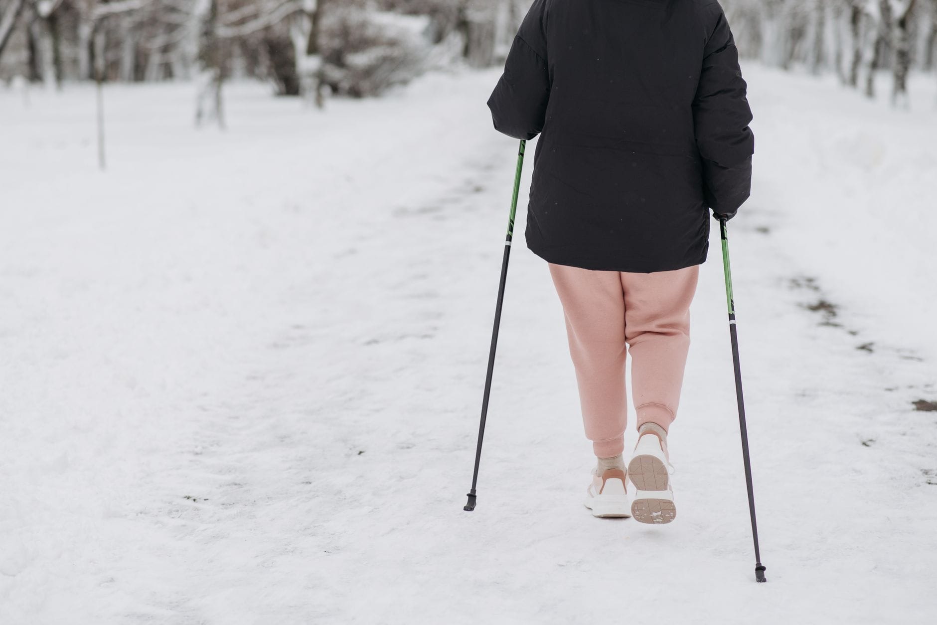 Jak dobrać kijki do nordic walking w teren górski, miejski i leśne ścieżki Osoba z kijkami idzie po zaśnieżonej ścieżce zimą
